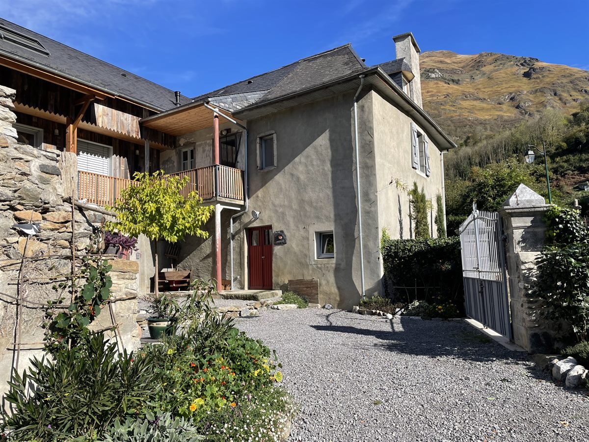 Cour et façade de la ferme béarnaise avec la montagne en arrière-plan