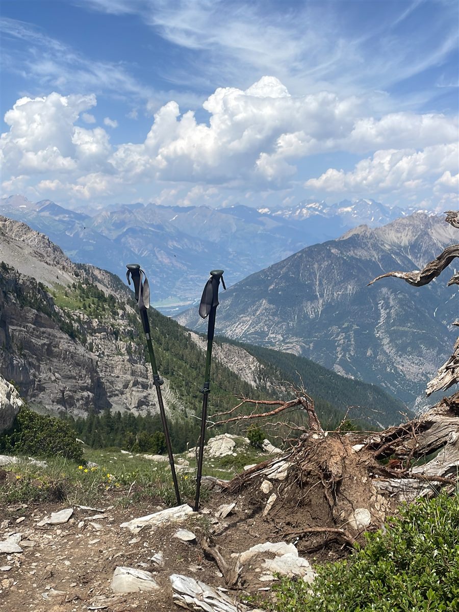 Bâtons de randonnée plantés sur un sentier de montagne surplombant la vallée